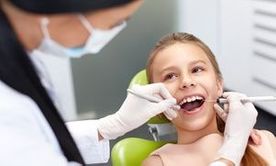 Teeth checkup at dentist's office. Dentist examining girls teeth in the dentists chair